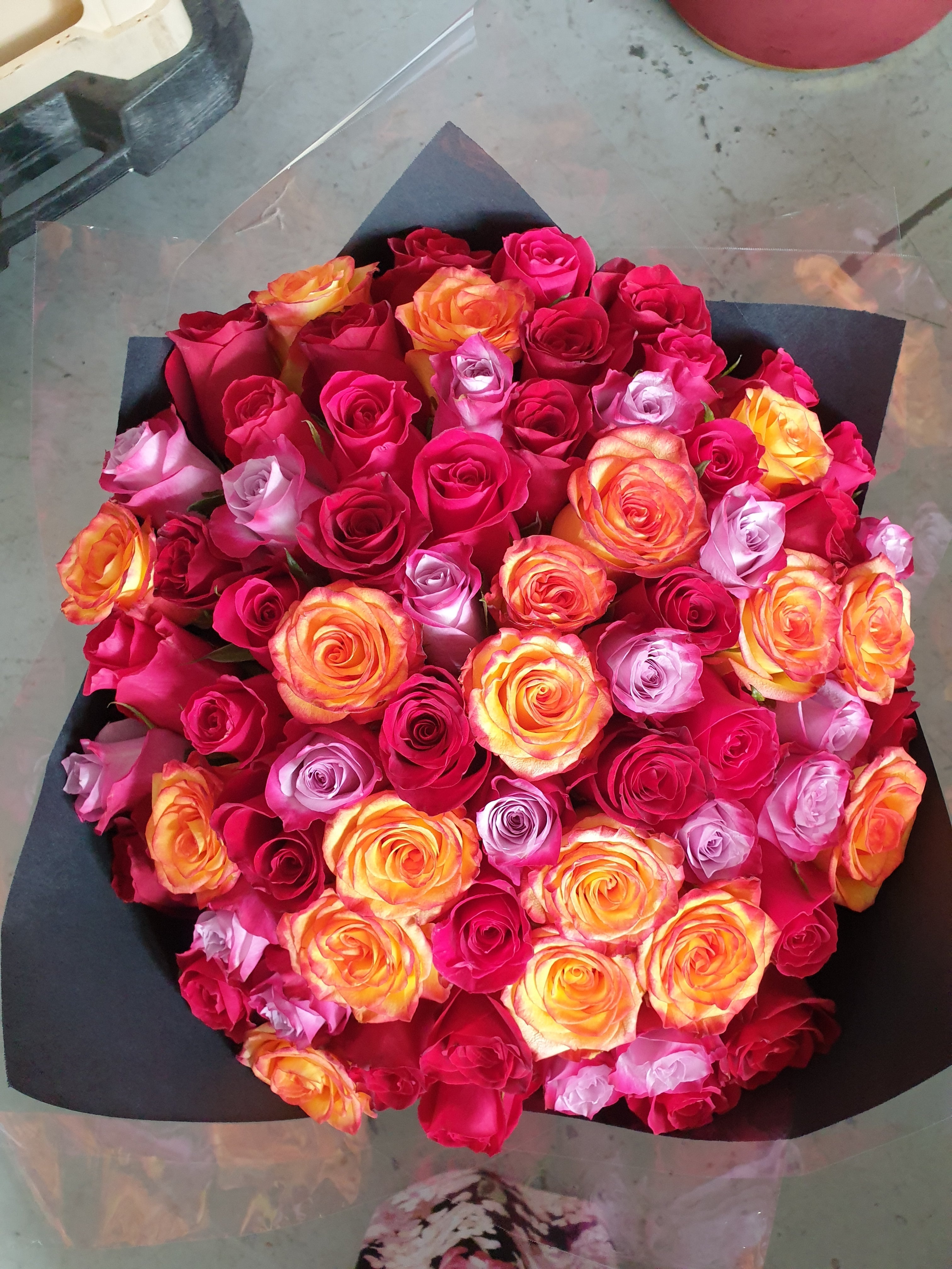 Bouquet of colorful roses in a heart shape on a gray surface
