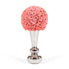 Decorative item with coral-colored rose ball on a silver stand against a white background