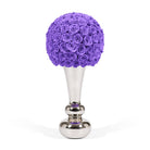 Purple floral arrangement on a silver stand against a white background