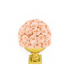 Decorative sphere made of pink roses on a gold base against a white background