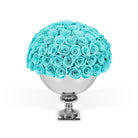 Bouquet of turquoise roses in a silver vase on a white background