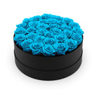 Black round box filled with blue roses on a white background