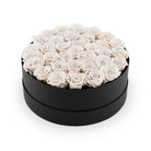 Round black box filled with white roses on a white background