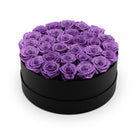 Black round box filled with purple roses on a white background