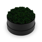 Black round box filled with dark green roses on a white background